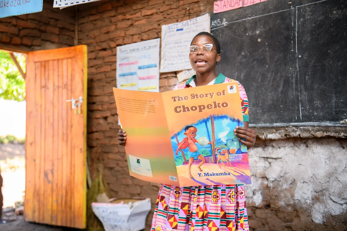 Girl holding up The Story of Chopeko during a read-aloud in Ntchisi, Malawi