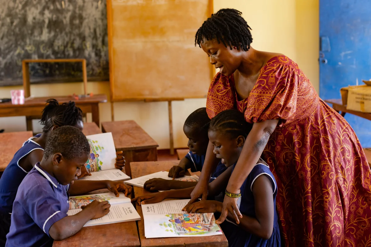 Teacher in traditional dress helping children read