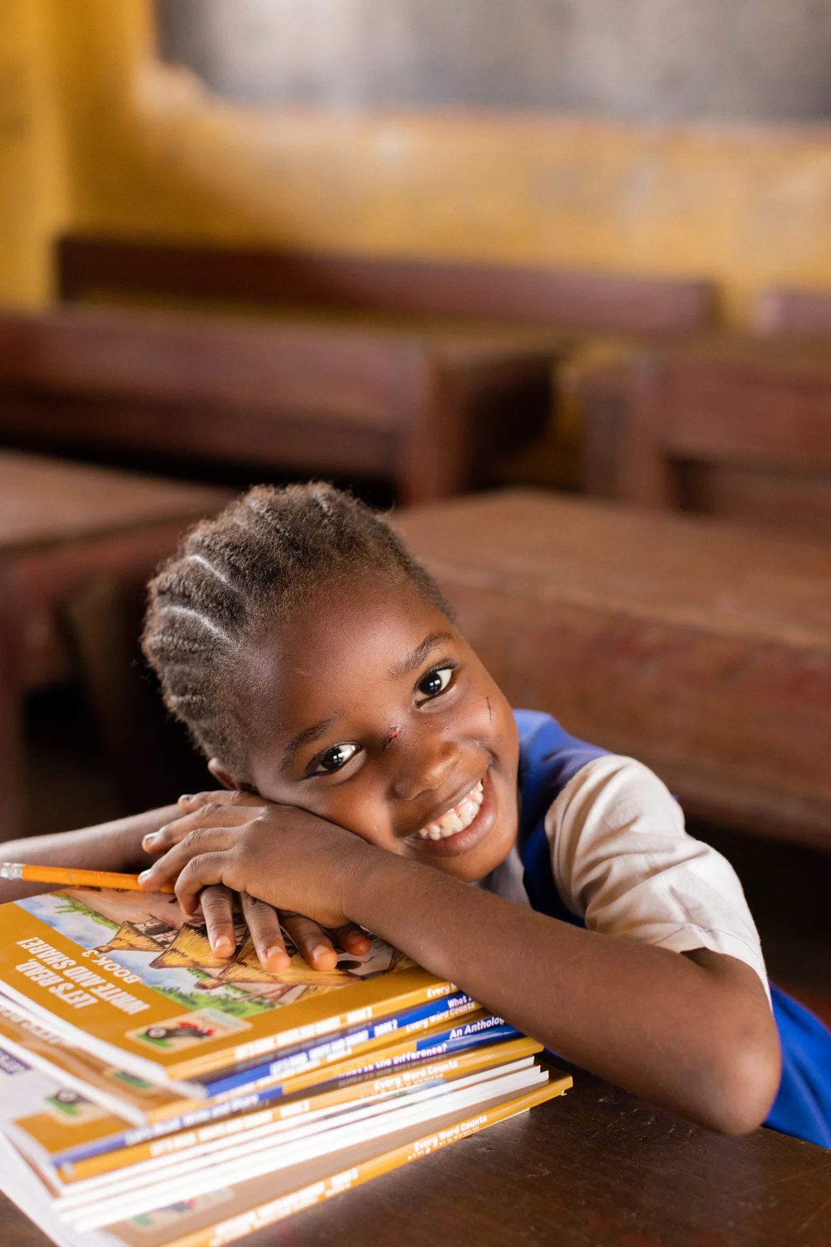 Girl resting on a stack of Let's Read and Write books