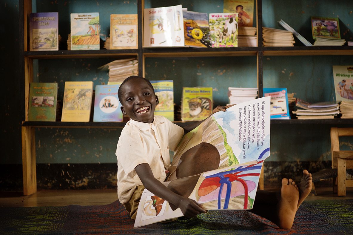 Child reading with large smile