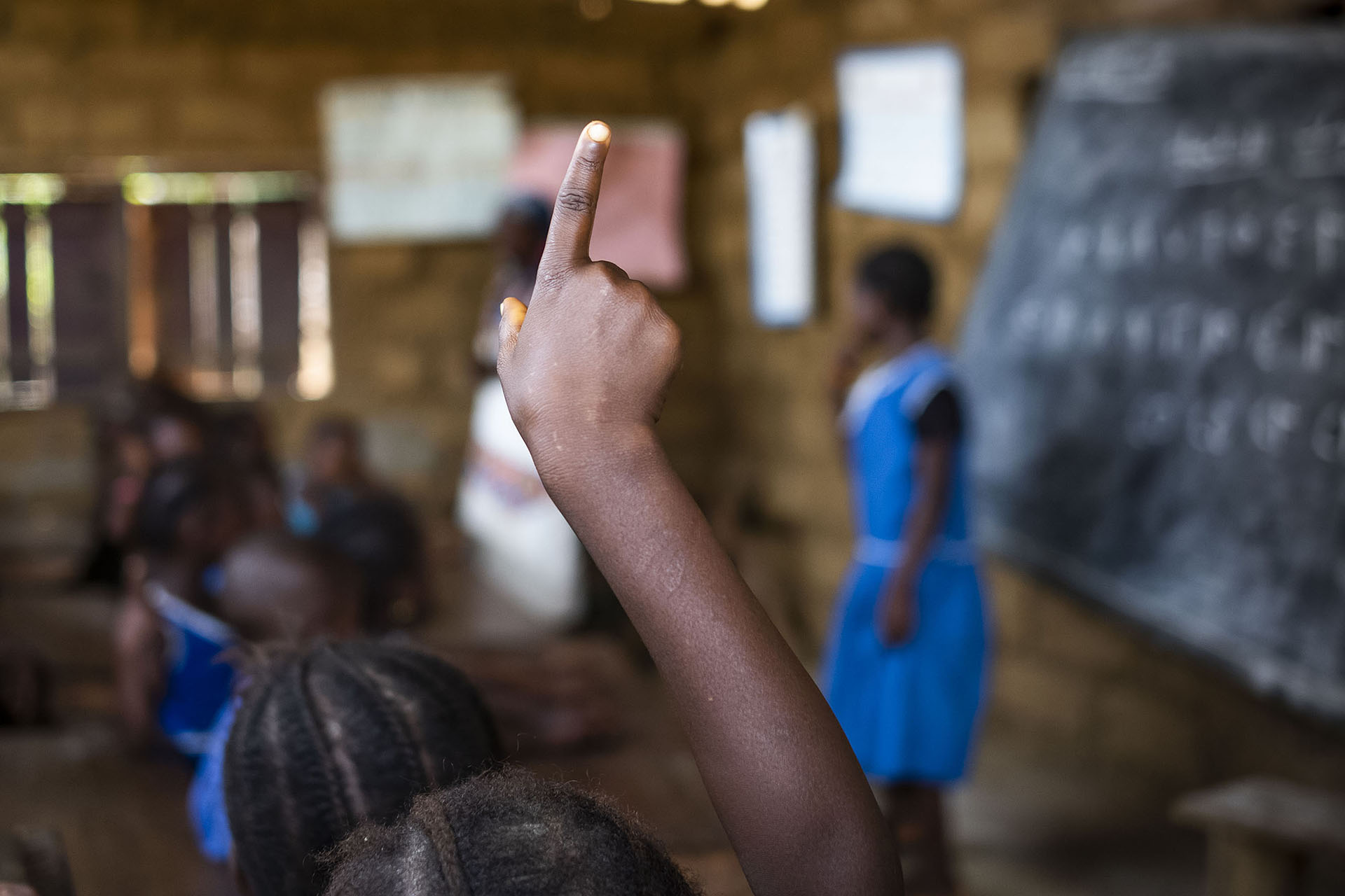 Young girl holding up hand in classroom