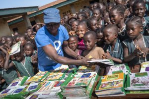 CODE Volunteer Handing Out Books To Children