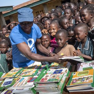 CODE Volunteer Handing Out Books To Children