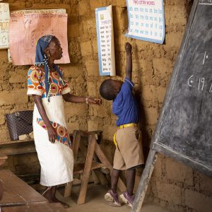Teacher With Child At The Front Of The Classroom